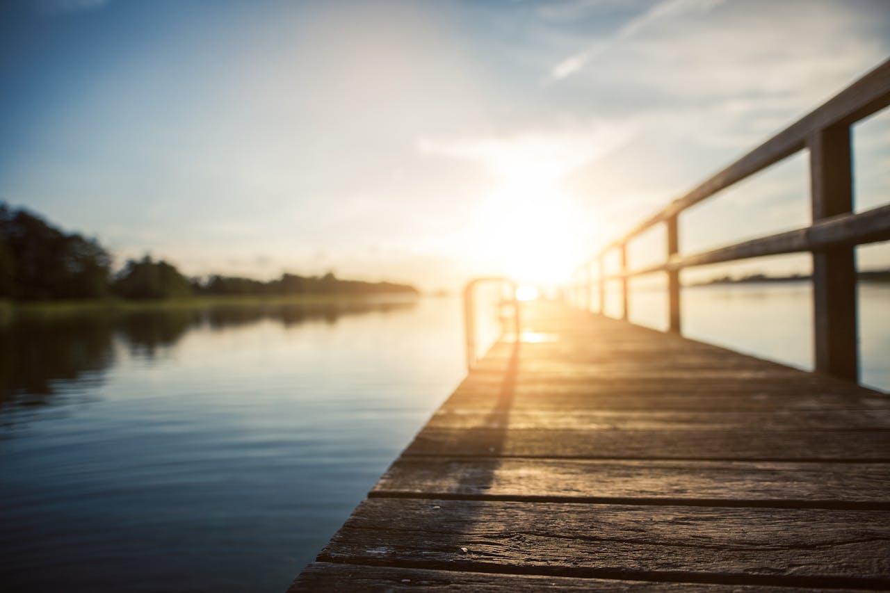 Peaceful sunset over a calm lake, captured from a wooden boardwalk in Kiel, Germany.